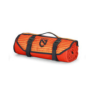 A rolled-up orange and red striped NEMO Equipment Victory™ Patio Waterproof Blanket with black straps and a carrying handle, shown on a white background.